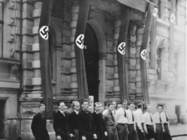 Studenten der Fachschaft Evangelische Theologie vor dem mit Hakenkreuzfahnen beflaggten Fakultätsgebäude Liebiggasse 5 (März…