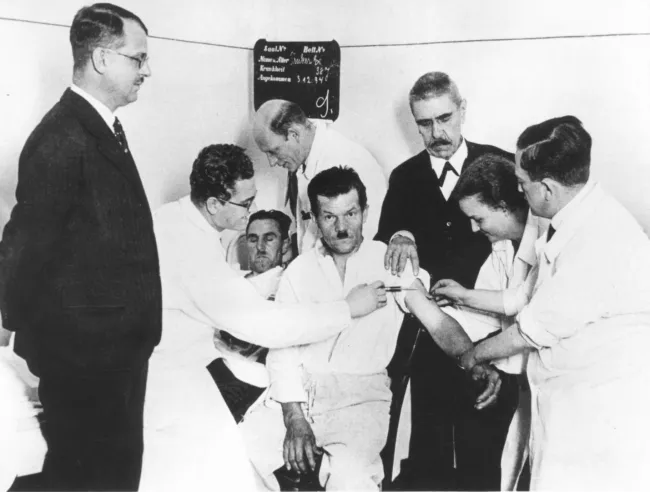 Julius von Wagner-Jauregg (1857–1940) mit Mitarbeitern an seiner Klinik bei einer Malariablutüberimpfung an einem Patienten